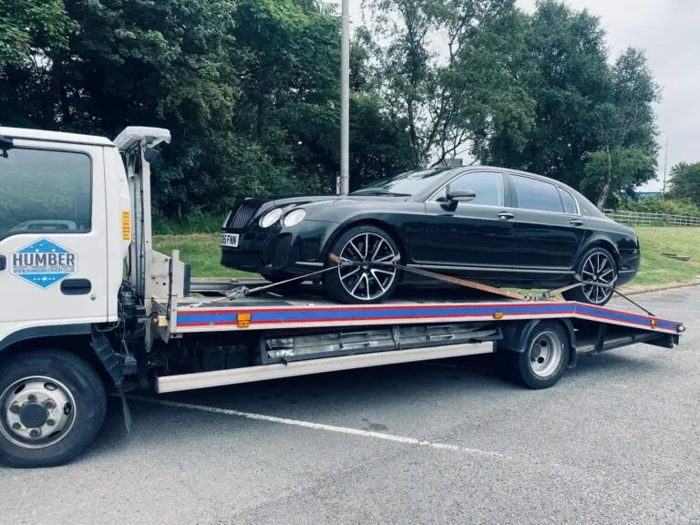 Black Bentley secured on Humber Recovery truck in Hull, parked near roadside trees