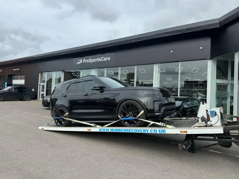 Black luxury SUV loaded onto Humber Recovery truck outside ProSports Cars dealership in Hull